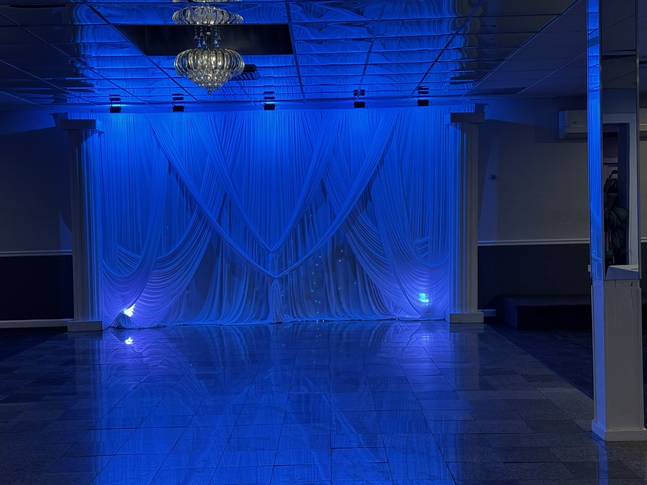 Dance floor with dramatic blue uplighting and draped backdrop