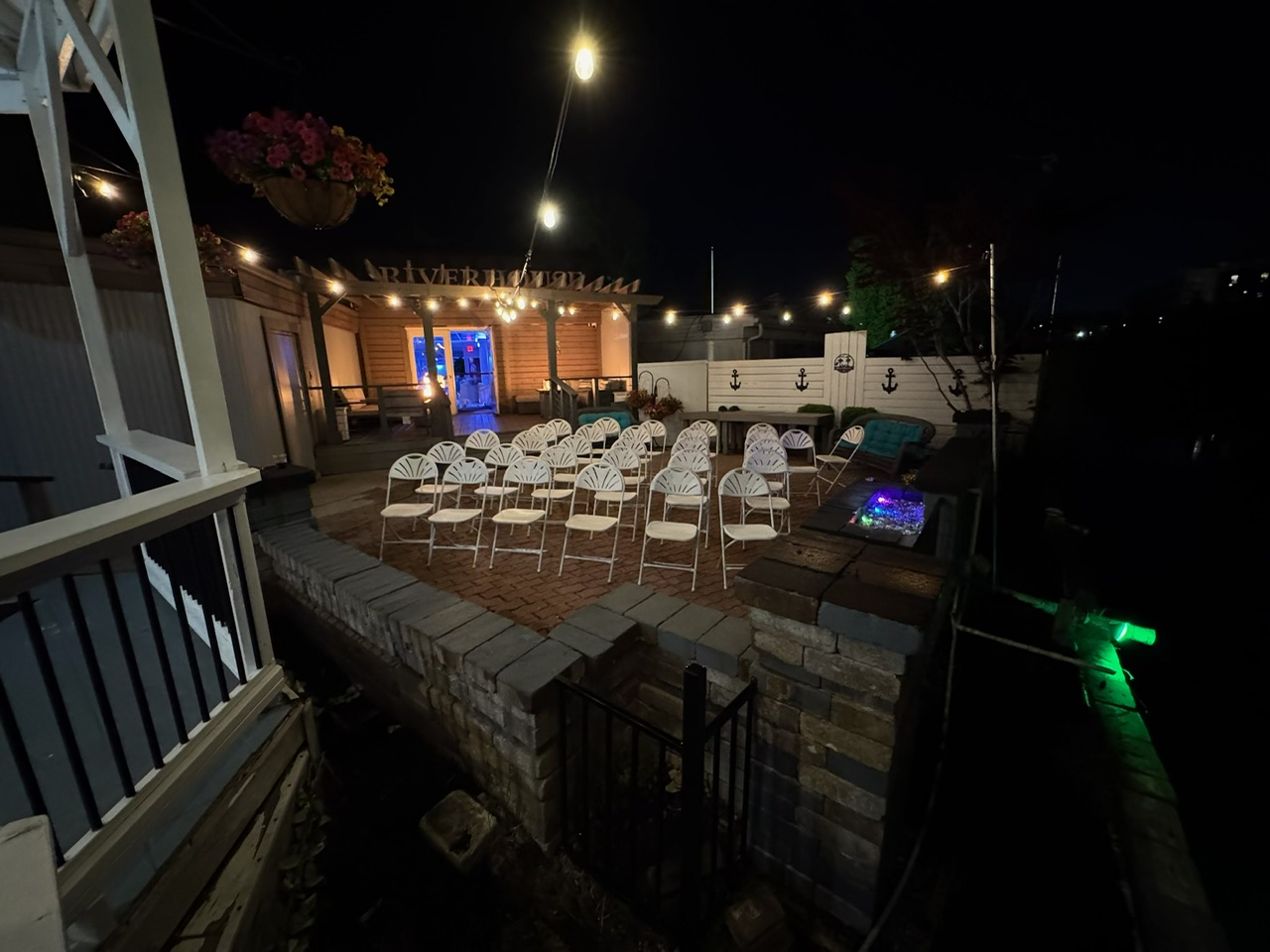 Riverhouse outdoor patio at night with string lights and ceremony chairs