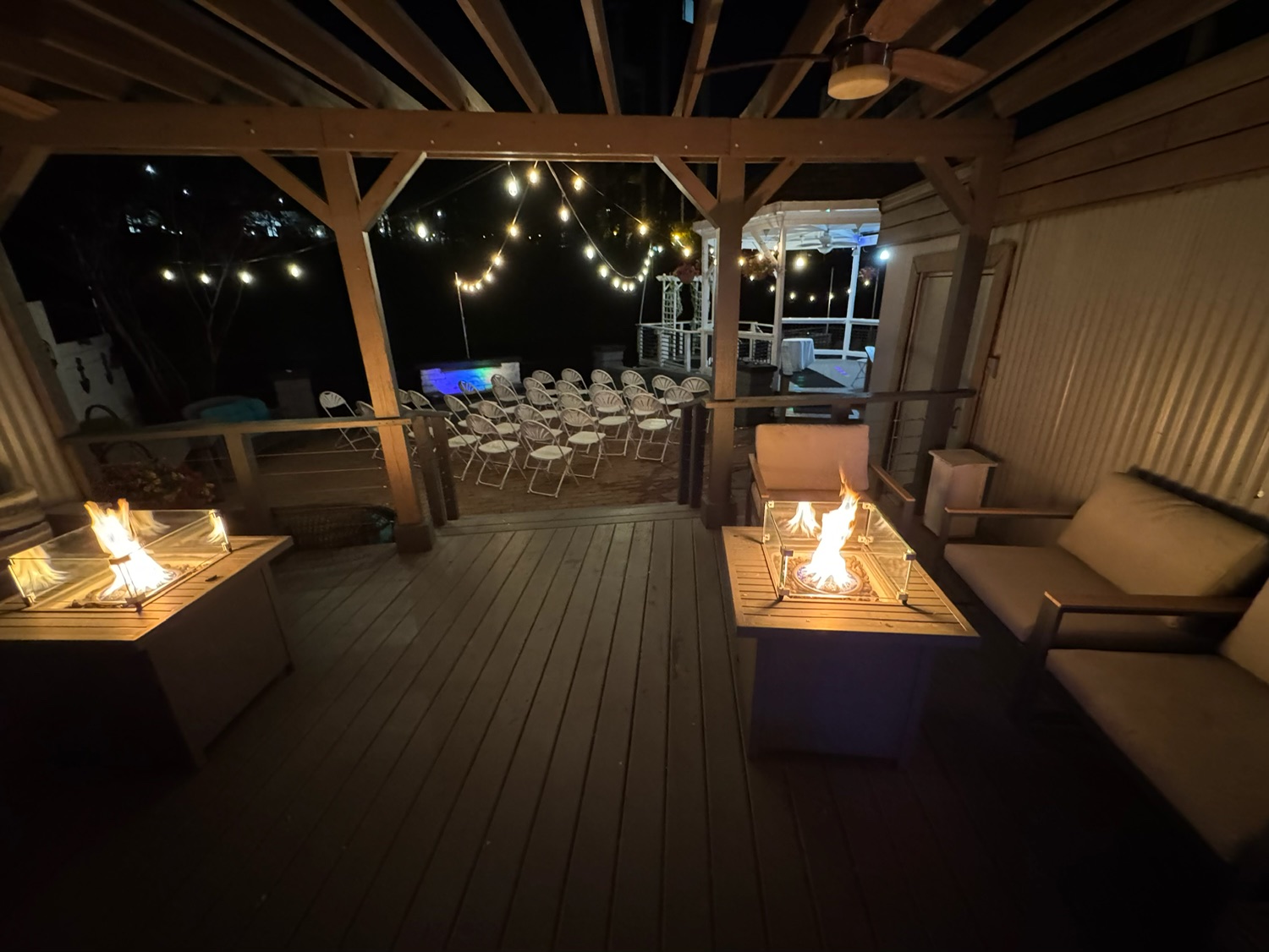 Covered outdoor lounge with fire pits and ceremony chairs in background